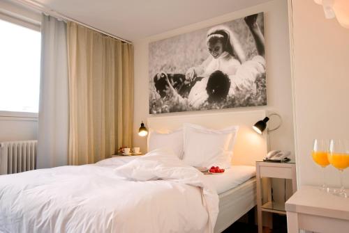 a bedroom with a white bed with a painting on the wall at Hotel Rival in Stockholm