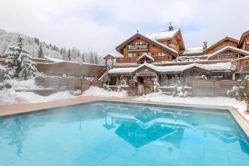 a house with a swimming pool in the snow at Hotel Eterlou in Méribel