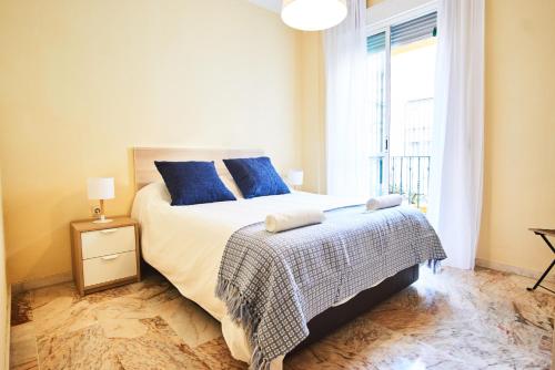 ein Schlafzimmer mit einem Bett mit blauen Kissen und einem Fenster in der Unterkunft Escoberos Courtyard Duplex by Valcambre in Sevilla