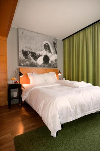 a bedroom with a white bed and a green curtain at Hotel Rival in Stockholm