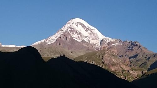 a large snow covered mountain with a blue sky at Guest House Tamta in Stepantsminda