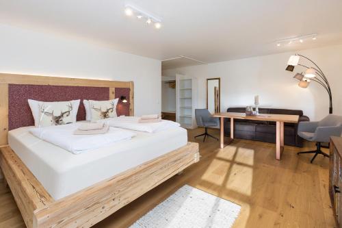 a bedroom with a large white bed and a desk at Landhaus Kössel in Füssen