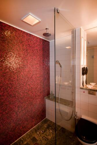 a bathroom with a shower and a red wall at Hotel Rival in Stockholm