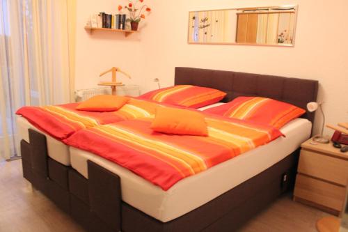 une chambre avec un lit avec des draps orange et jaune dans l'établissement Villa Concordia Apartment Hiddensee, à Binz