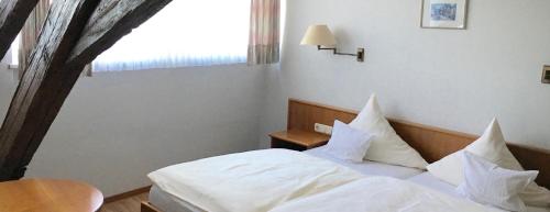 Schlafzimmer mit einem Bett mit weißer Bettwäsche und einem Fenster in der Unterkunft Gasthof Anker in Miltenberg