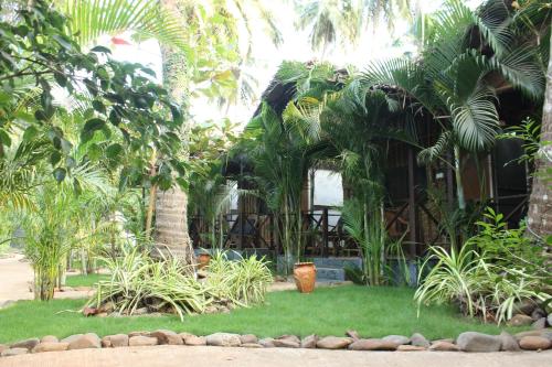 a garden with palm trees and a building at Sea Shades Cottages I Private Jacuzzi in Palolem