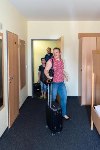 a man standing in a hallway with a suitcase at Familienhotel Citylight in Berlin