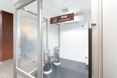 una puerta de cristal con una señal en un edificio en Pearl Hotel Shinjuku Akebonobashi en Tokio