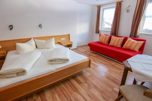 a bedroom with a bed and a red couch at Apart Alpenstern in Nauders