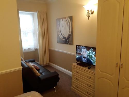 a living room with a television on a dresser at The Pack o' Cards in Combe Martin
