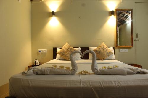 Dos cisnes hechos de toallas en una cama en Sea Shades Palolem Resort, en Palolem