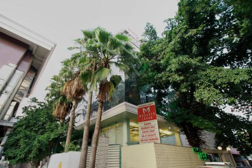 a no parking sign in front of a building with palm trees at Monarch Luxur - Infantry Road in Bangalore