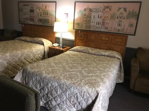 una camera d'albergo con due letti e una lampada di Village Inn a Lovingston