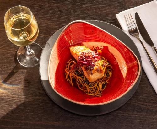 a red bowl of pasta and a glass of wine at Copthorne Hotel Plymouth in Plymouth