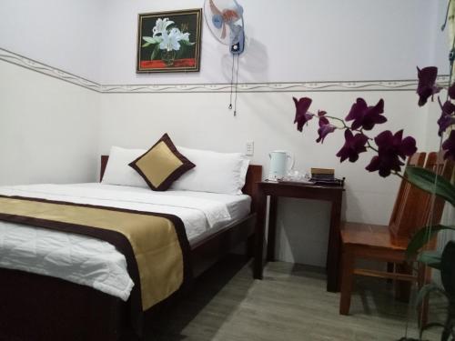 a bedroom with a bed and a table and flowers at Duong Hieu Guesthouse in Phu Quoc