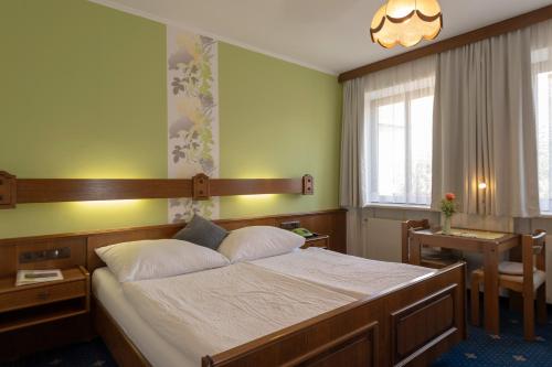 Schlafzimmer mit einem Bett, einem Tisch und einem Fenster in der Unterkunft Pension Wienerstub'n in Baden