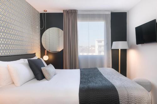 a hotel room with a bed and a window at Hôtel Innes by HappyCulture in Toulouse