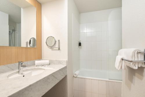 a bathroom with a sink and a tub and a mirror at Hôtel Innes by HappyCulture in Toulouse