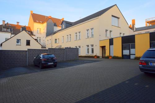 ein Parkplatz mit zwei Autos vor den Gebäuden in der Unterkunft Gästehaus Rohleder in Velbert