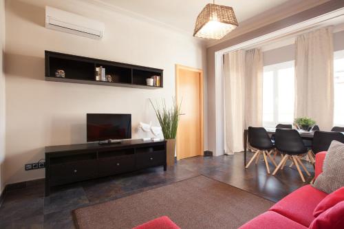 salon z czerwoną kanapą i telewizorem w obiekcie EasySleep Eixample w Barcelonie