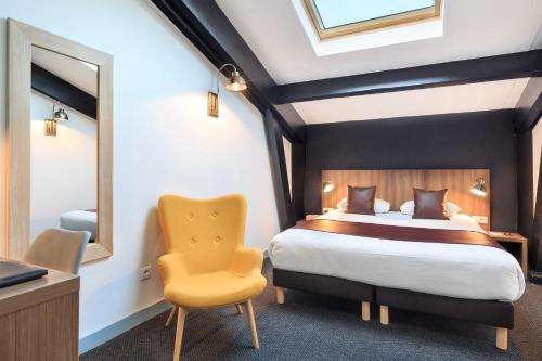a bedroom with a bed and a yellow chair at Hôtel Innes by HappyCulture in Toulouse
