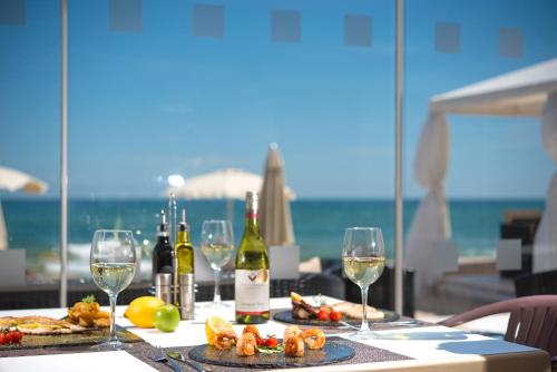 a table with wine glasses and food and the ocean at Effect Algara Beach Resort - Ultra All Inclusive and Free Parking in Kranevo