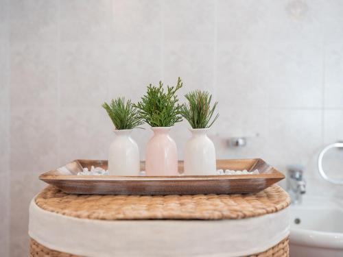 Trois vases blancs avec des plantes sur une table dans une salle de bains dans l'établissement Marenklhof, à Monguelfo-Tesido