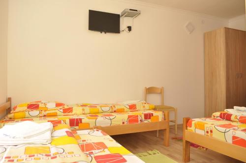 a room with two beds and a tv on the wall at Apartments & Rooms Bojic in Kolašin