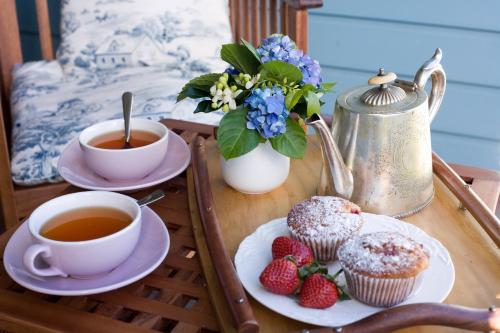 a table with cups of tea and muffins and strawberries at The Spotted Chook and Amelie's Petite Maison in Montville