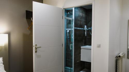 a bathroom with a shower and a white door at Hôtel des Arcades in Reims
