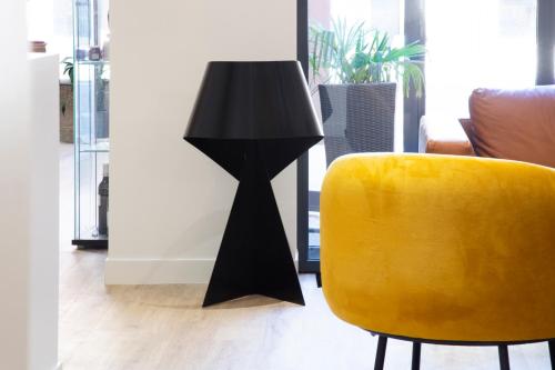 a black lamp sitting next to a yellow chair at Hôtel Innes by HappyCulture in Toulouse