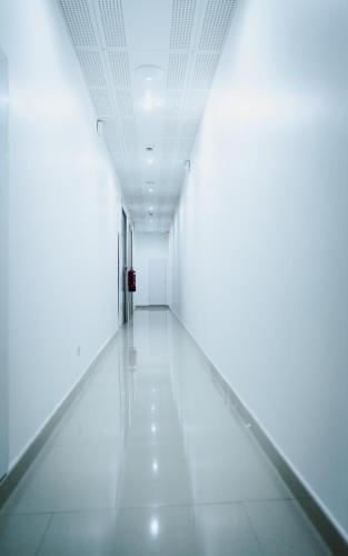 an empty hallway with white walls and white floors at Hôtel des Arcades in Reims