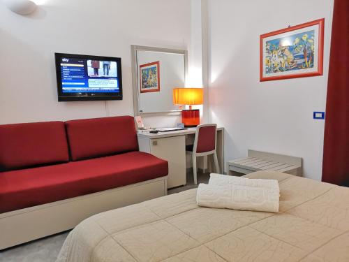 a hotel room with a bed and a couch and a desk at Hotel La Battigia in Alcamo Marina