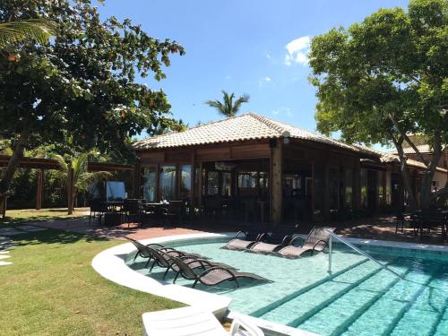 een zwembad met ligstoelen en een huis bij Carambola Hotel in Arraial d'Ajuda