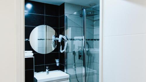 a bathroom with a shower and a sink and a mirror at Hôtel des Arcades in Reims