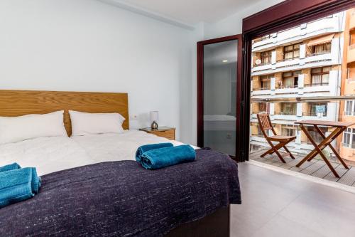 ein Schlafzimmer mit einem Bett und ein Balkon mit einem Tisch in der Unterkunft Canteras Luxury Beach Apartments in Las Palmas de Gran Canaria