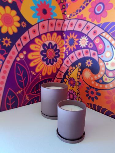 two candles on a table in front of a colorful wall at La Quinta Glamping - Lago de Tota in Cuítiva