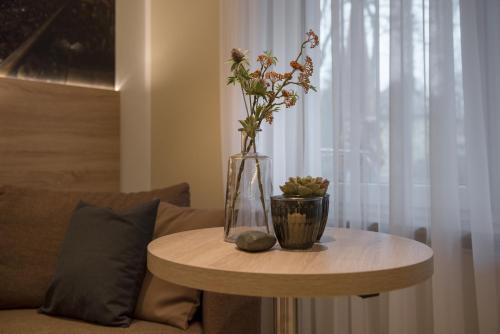a vase with flowers on a table next to a couch at Hotel-Restaurant Barbarossahof in Kaiserslautern