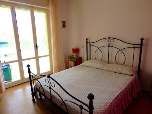 een slaapkamer met een bed met een zwart frame en ramen bij M156 - Marcelli, trilocale con giardino a 80mt dal mare in Marcelli