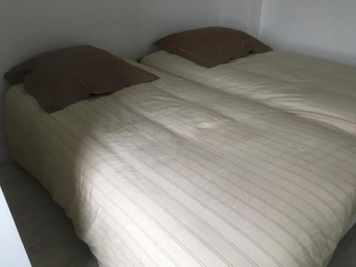 ヴィムルーにあるGîte Le Welcomeのベッド(白いシーツ、茶色の枕付)