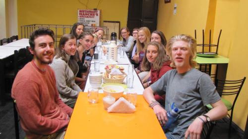 un grupo de personas sentadas en una mesa con un pastel en Hostel Imperial BACKPACKER, en Cusco