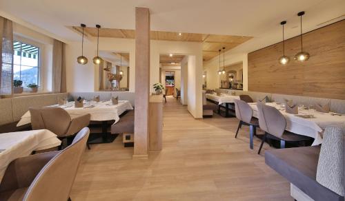 a dining room with white tables and chairs at Hotel Castel - pure Lebensfreude in Serfaus