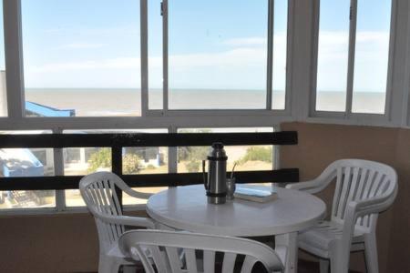 una mesa y sillas blancas con mesa y ventanas en Departamento en San Bernardo, partido de la costa en San Bernardo