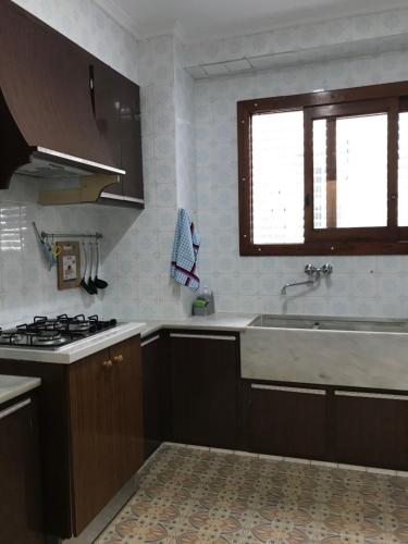 a kitchen with brown cabinets and a sink and a window at Bonito piso en el centro de Benaguacil in Benaguacil