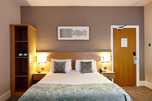 a bedroom with a bed with two night stands and two lamps at Linton Lodge a BW Signature Collection Hotel in Oxford