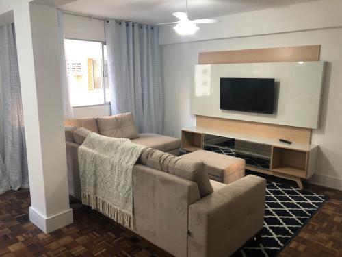 uma sala de estar com um sofá e uma televisão de ecrã plano em Prédio frente mar 3 quartos Balneário camboriú BrisaMarBC3 no Balneário Camboriú