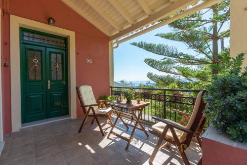 a porch with a green door and chairs and a table at Aerokaria Studio in Ágios Márkos