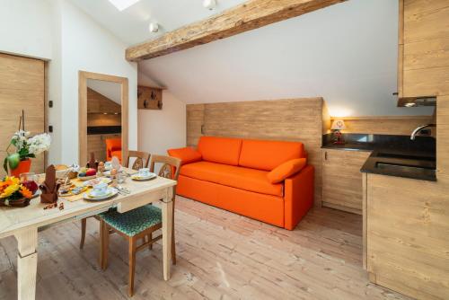 a living room with an orange couch and a table at Hotel Haus Michaela in Sappada