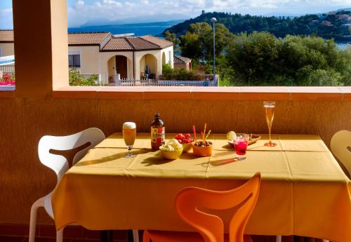 a table with a yellow table cloth and drinks on it at Residence Appartamenti Caffarena in Àrbatax