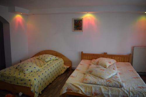 two beds in a room with lights on the wall at Casa Parvu in Lunca Mare
